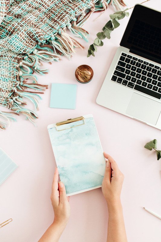Flat lay home office desk. Female workspace with clipboard, laptop, eucalyptus branch, accessories on pink background. Top view feminine background. Lifestyle blog hero.